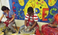 Young students from the Art Troupe program using pottery wheels.