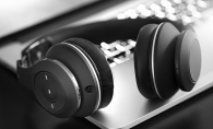 In this black and white photo, a pair of wireless headphones rests on a laptop.