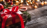 A wrapped Christmas present sits near a string of lights