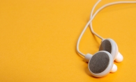 A pair of white headphones on a yellow background.