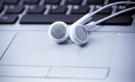 A pair of white headphones rest on a laptop.