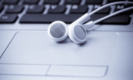 A pair of white headphones sit on a computer keyboard.