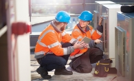 Two HVAC technicians work on a unit.