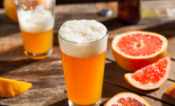 A local summer beer sits on a patio table next to a grapefruit.