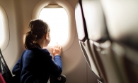 A girl looks out a plane window on a family vacation.