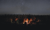 A group of kids sit around a campfire telling scary stories.