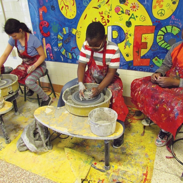 Young students from the Art Troupe program using pottery wheels.