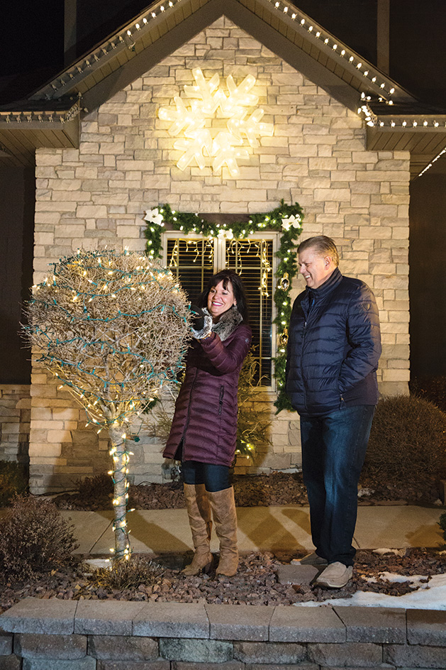 Lori and Bill Beach decorate a tree with Christmas lights.