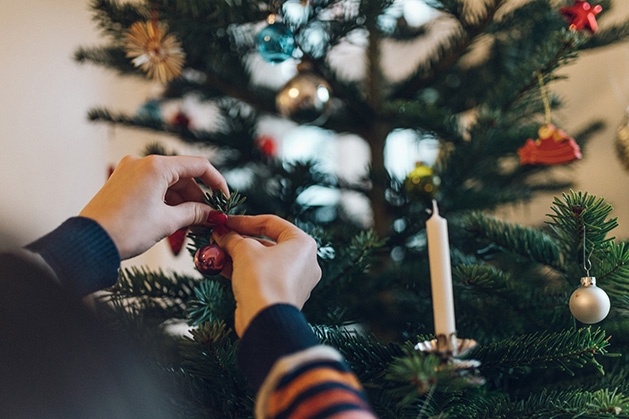 Someone hangs an ornament on a Christmas tree