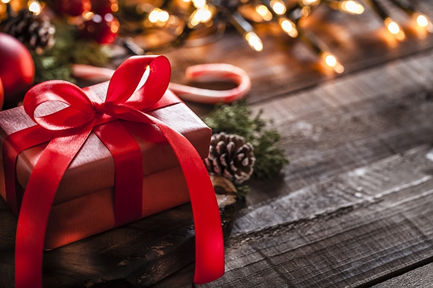 A wrapped Christmas present sits near a string of lights