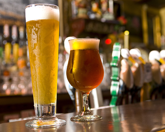 Two summer IPAs sit on a bar.