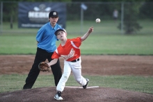 An umpire-in-training from Walks and Balks watches a pitcher on the mound.