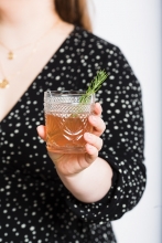 A woman holds a gin old fashioned.