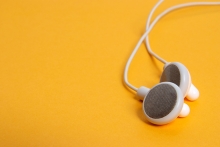 A pair of white headphones on a yellow background.