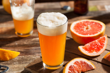 A local summer beer sits on a patio table next to a grapefruit.