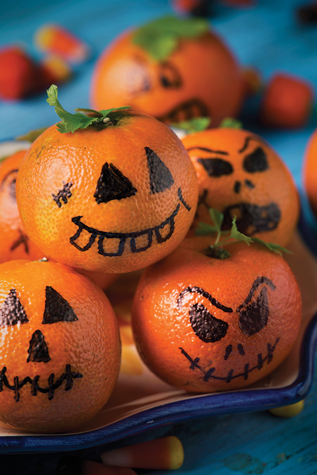 Clementines with jack-o'-lantern faces drawn on,