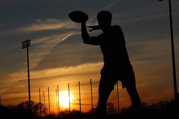 The silhouette of a boy playing football.