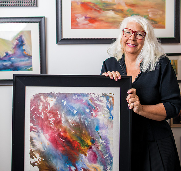 Watercolor artist CJ Longaecker poses with some of her paintings.